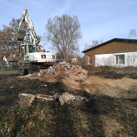 Ein weißer Bagger trägt den Schutt von einem Grundstück ab