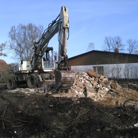 Ein weißer Bagger nimmt Abrissarbeiten auf einem Grundstück vor