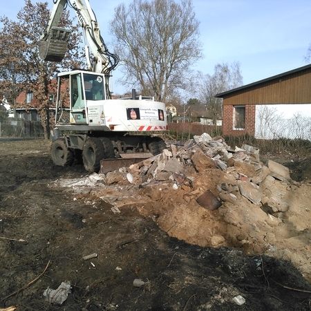 Ein weißer Bagger trägt den Schutt von einem Grundstück ab